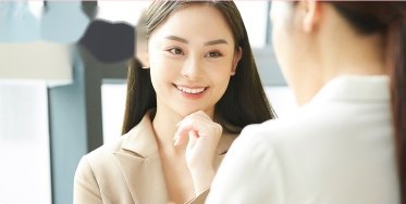 明るいオフィスで向かい合って会話する二人の女性