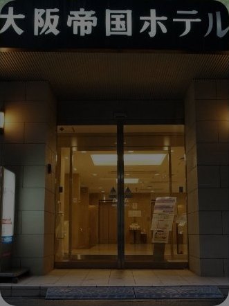 오사카 테이코쿠 호텔 — 大阪帝国ホテル 간판이 걸린 야간 입구와 따뜻한 조명의 유리문