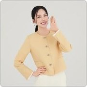 연노랑 라운드넥 카디건과 흰 하의를 입은 여성 모델이 웃으며 오른손을 얼굴 옆에 들어 알리는 제스처를 하고 왼손은 허리에 얹고 서 있다