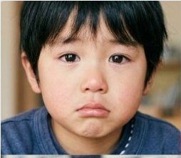 泣きそうな表情で口をへの字にした日本人の少年のバストアップ