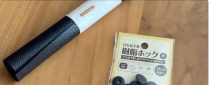 木目のテーブルに置かれた黒い革調の筒状カットクロスと、黄色いパッケージの樹脂ホックの袋・黒いホック部品