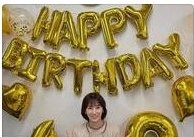 「HAPPY BIRTHDAY」の金色バルーン文字を背にした女性のスナップ